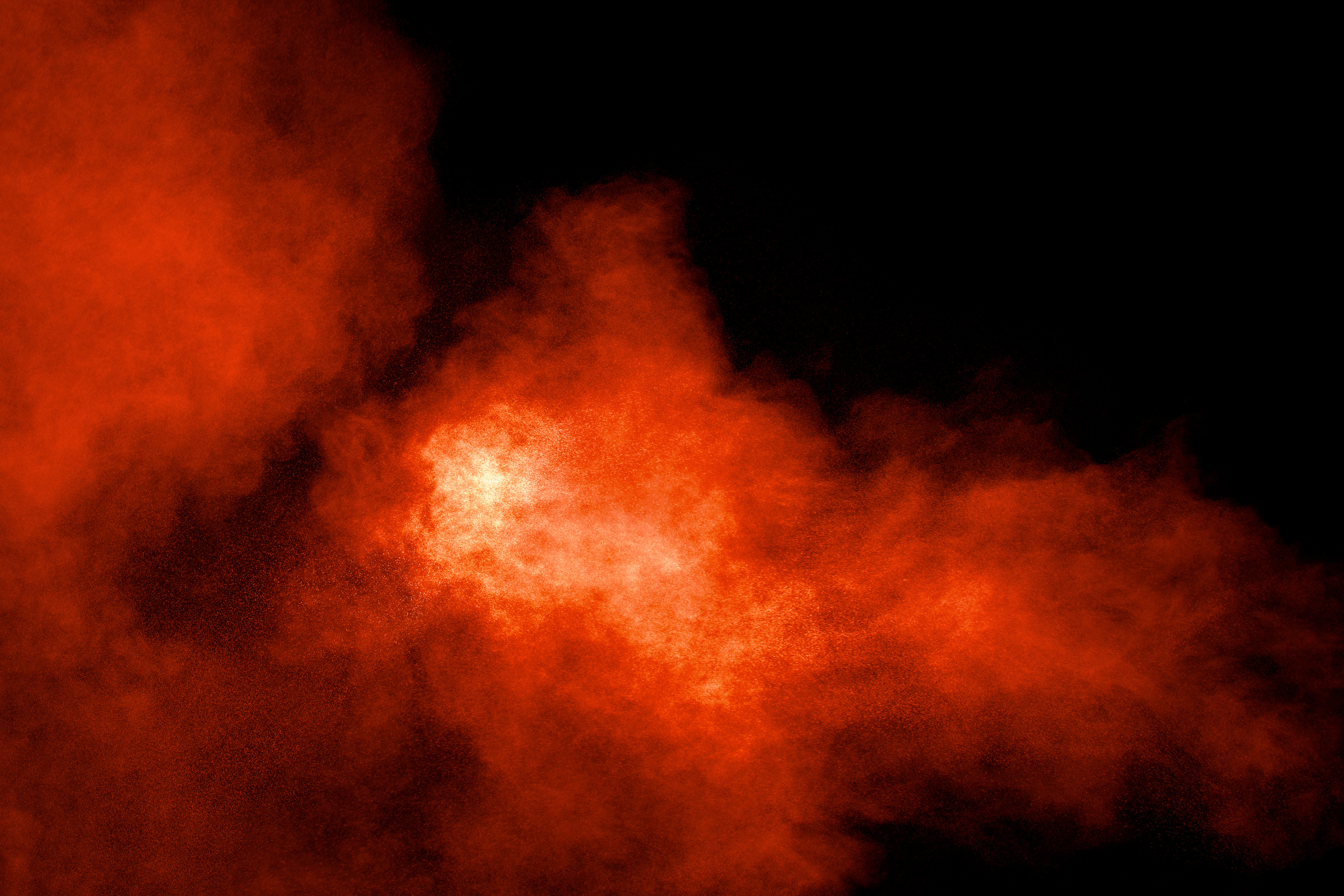 Abstract explosion of orange dust on black background.Freeze motion of orange powder burst.